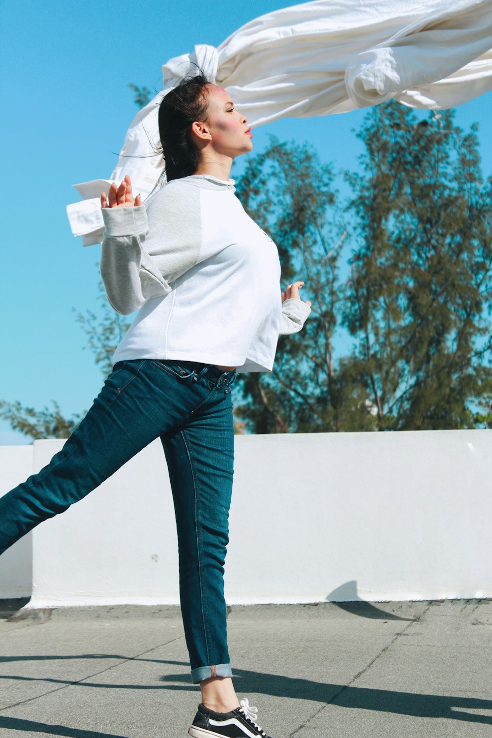 woman in white long sleeve shirt and blue denim jeans holding white ceramic mug