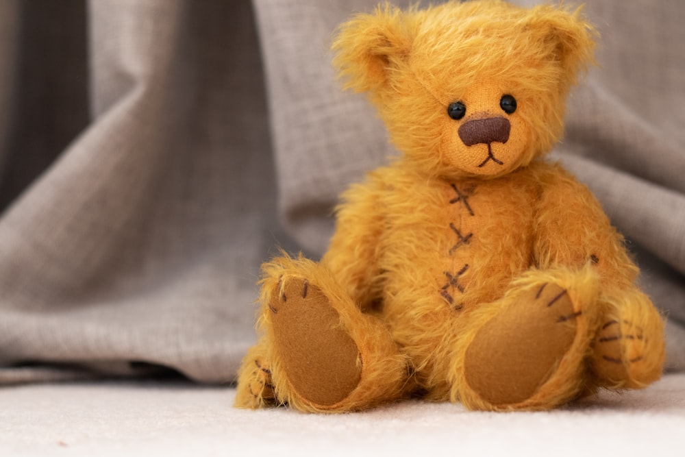 brown teddy bear on white textile
