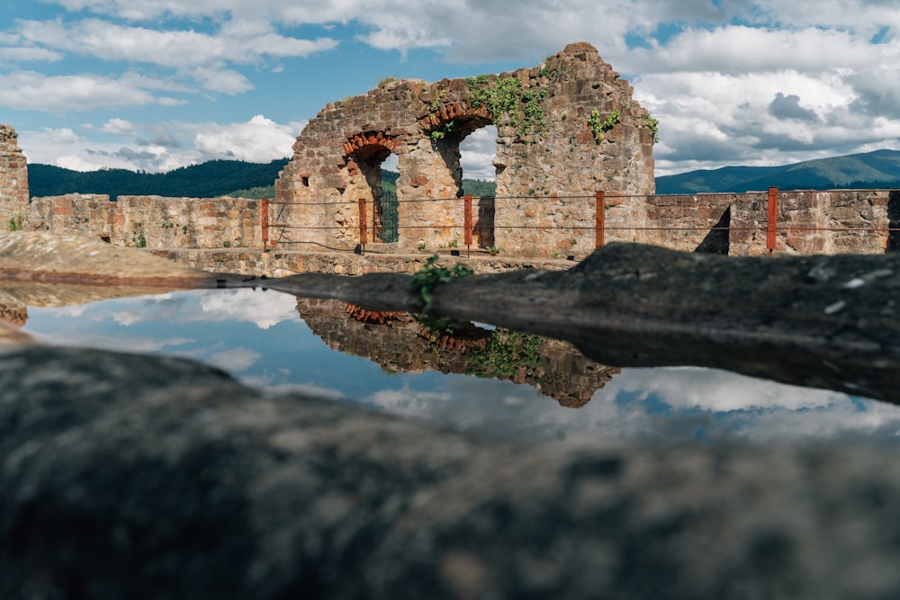 brown concrete building on brown rock formation near body of water under white clouds and blue