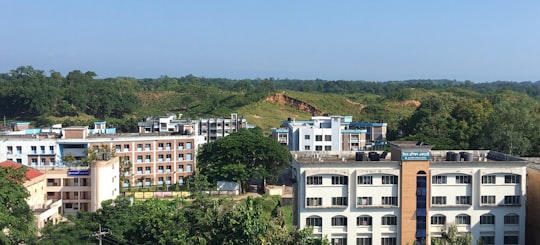 white and brown concrete building near green trees during daytime in Sylhet Bangladesh