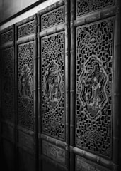 Elaborately carved wooden panels with intricate patterns and decorative motifs, showcasing traditional craftsmanship. The panels are made with detailed designs and feature artistic scenes inside ornate frames.