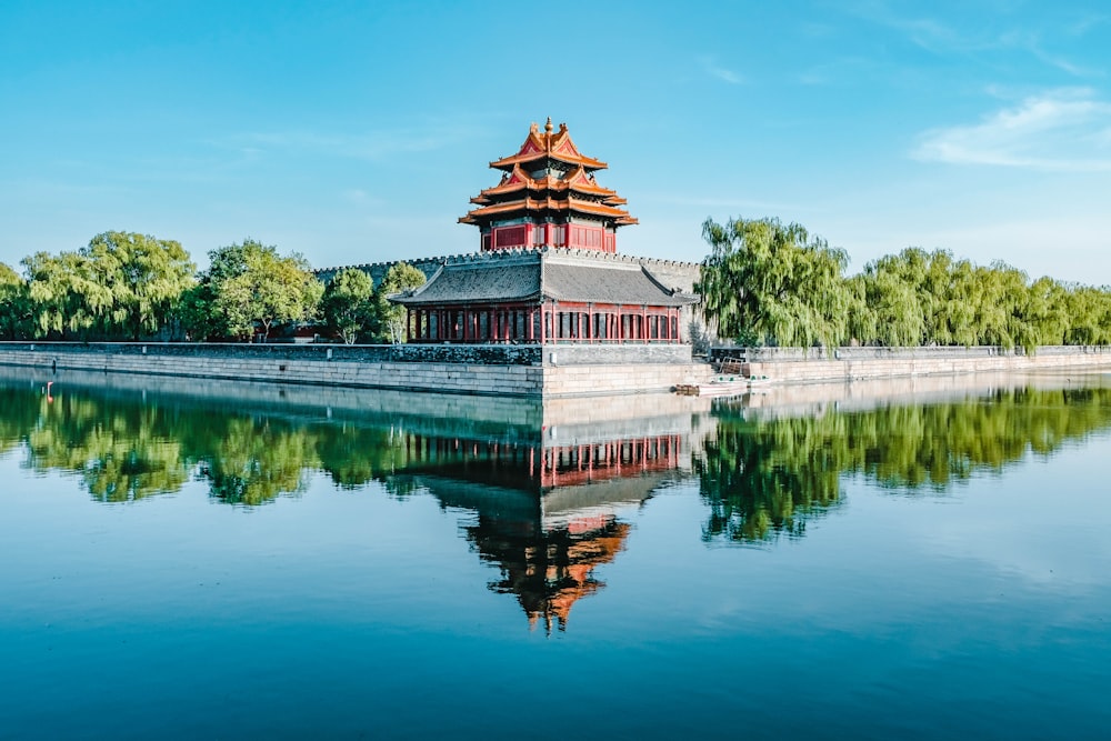 a large building sitting on top of a lake next to a forest