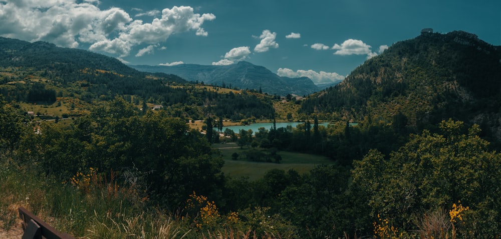 green trees and mountains under blue sky and white clouds during daytime