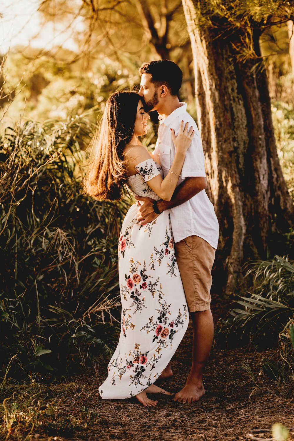homem e mulher que se beijam perto da árvore marrom durante o dia
