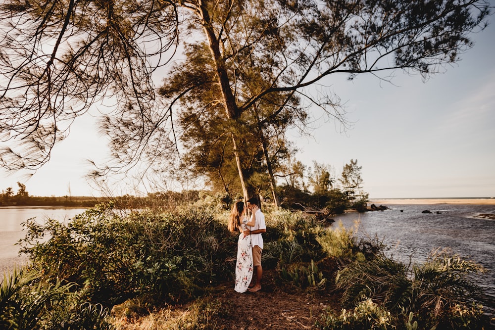 woman in white dress standing on green grass field near body of water during daytime