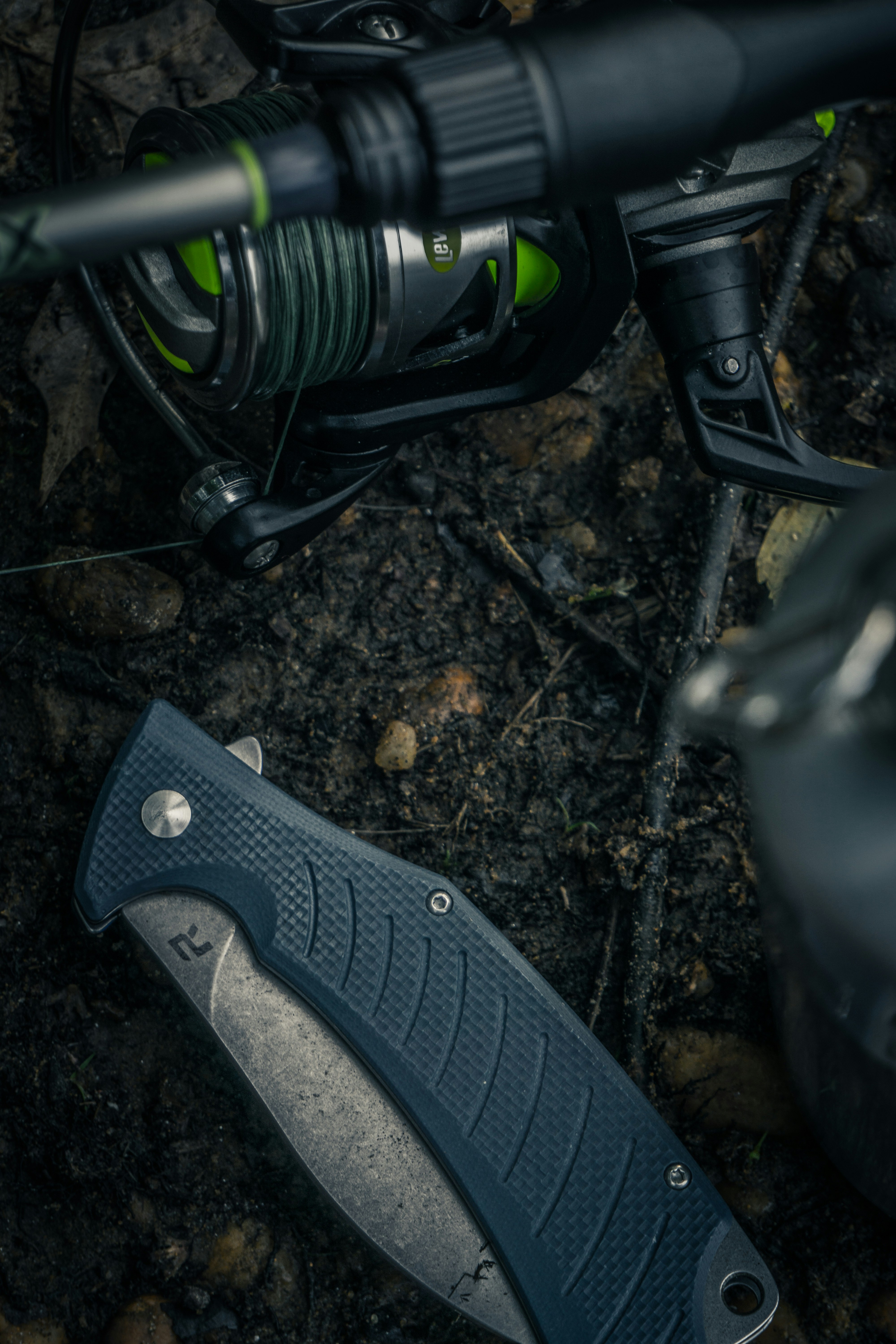 black and gray folding knife on black and brown soil