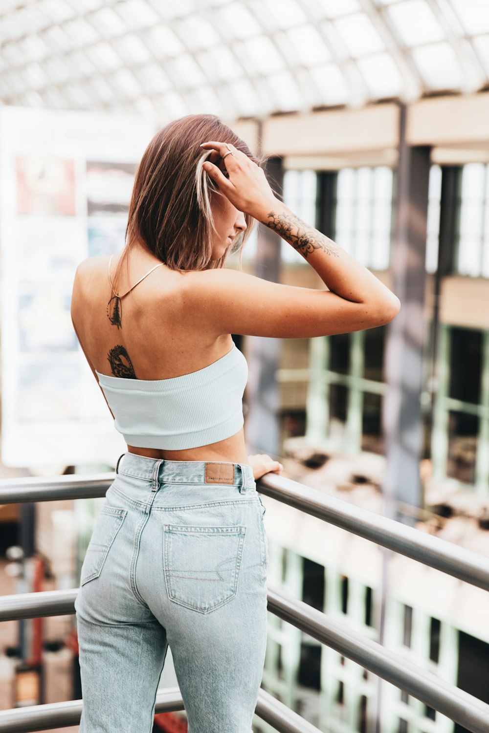 woman in white crop top and blue denim jeans standing near railings during daytime