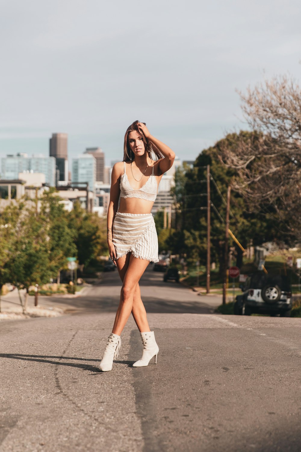 woman in white tank top and white skirt standing on road during daytime