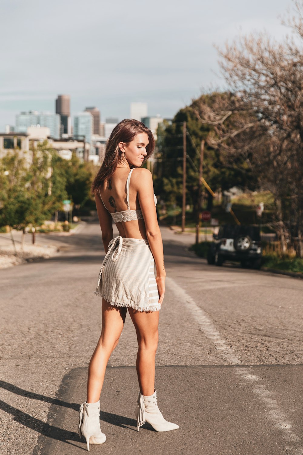 woman in white tube dress standing on road during daytime