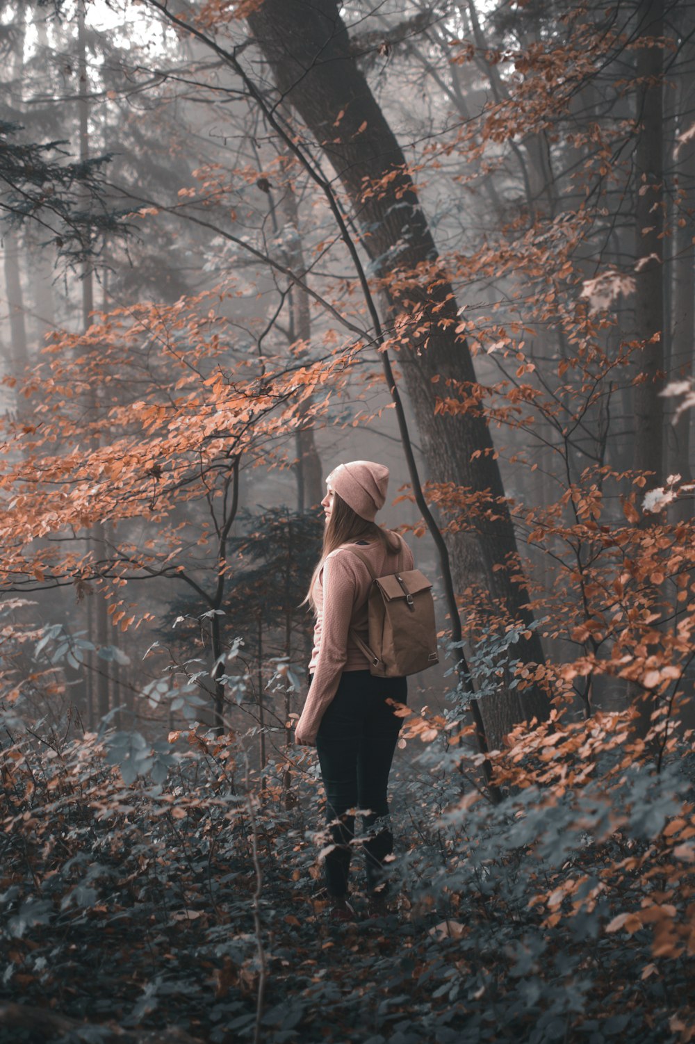 woman in brown jacket standing under brown tree during daytime