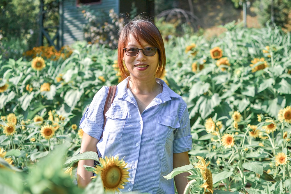 woman in blue button up shirt holding sunflower