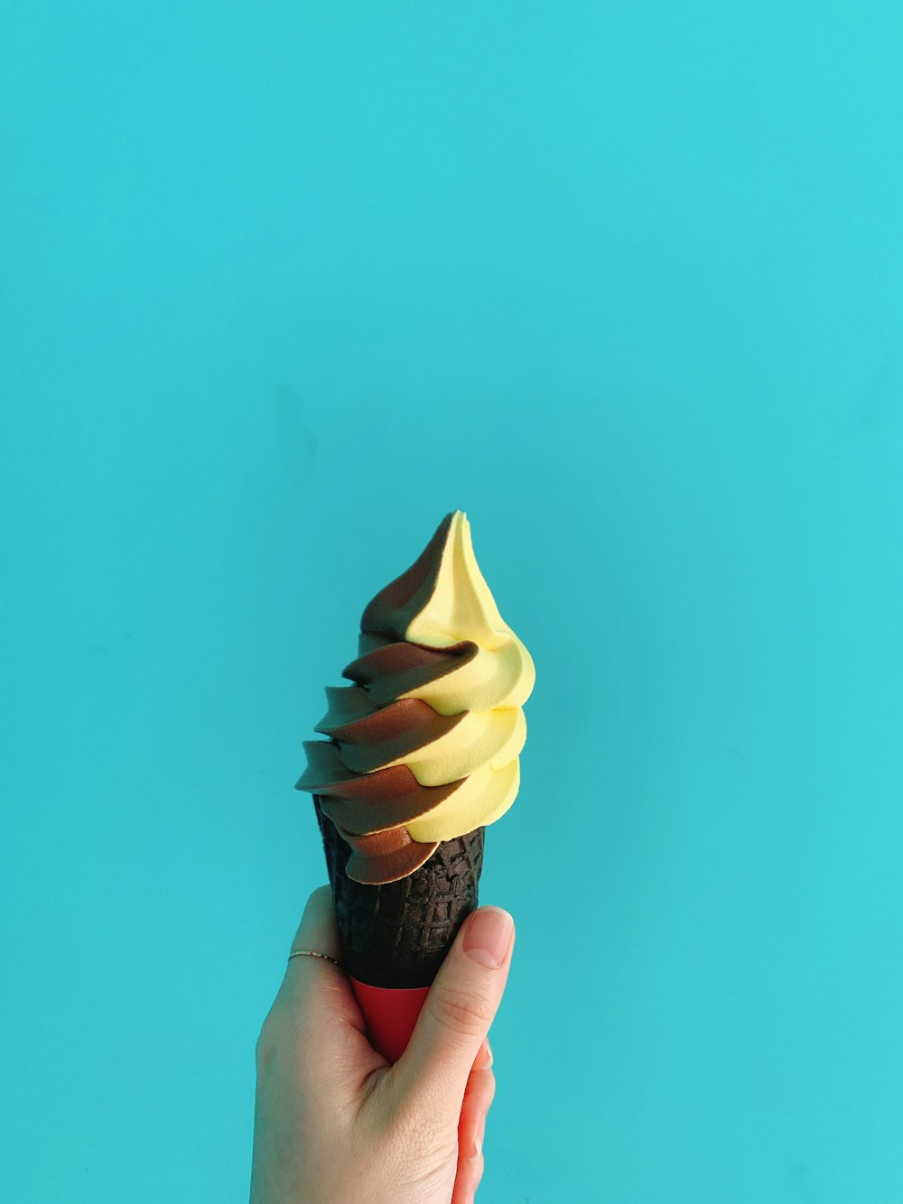 person holding yellow ice cream cone