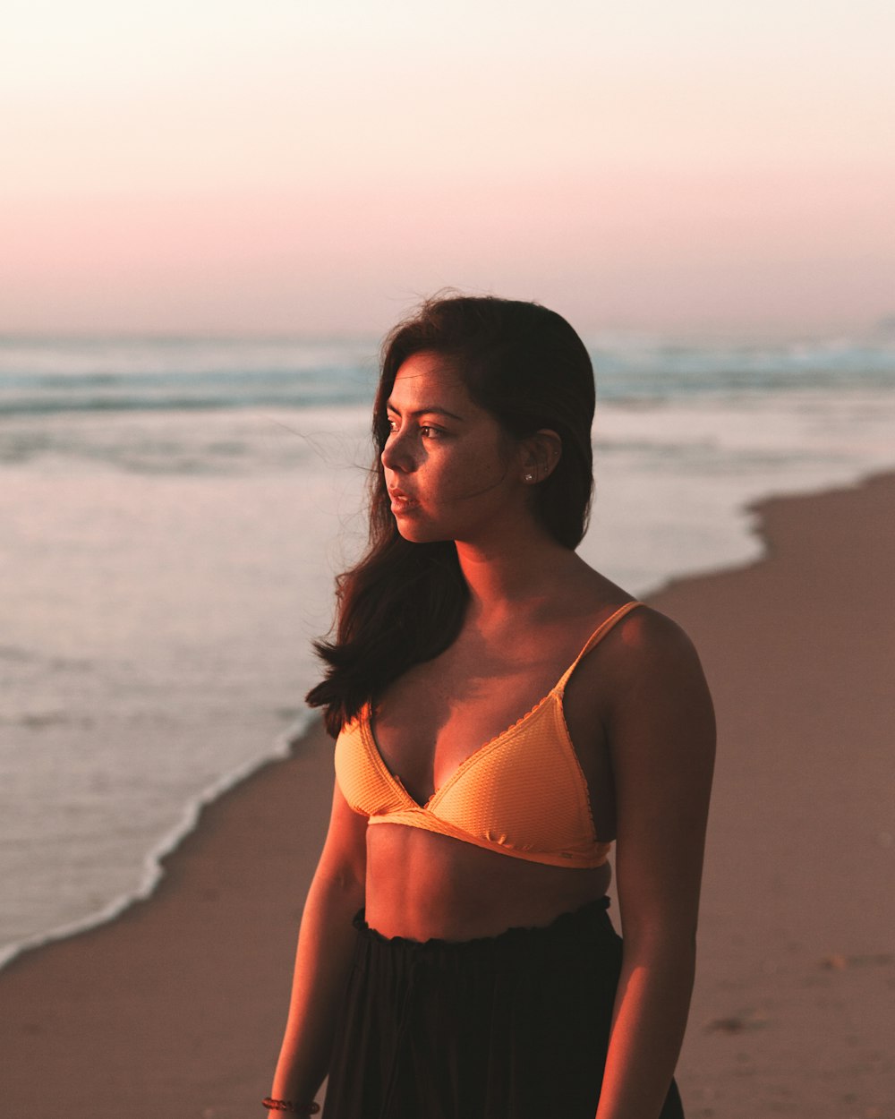 woman in white bikini top standing on beach during sunset