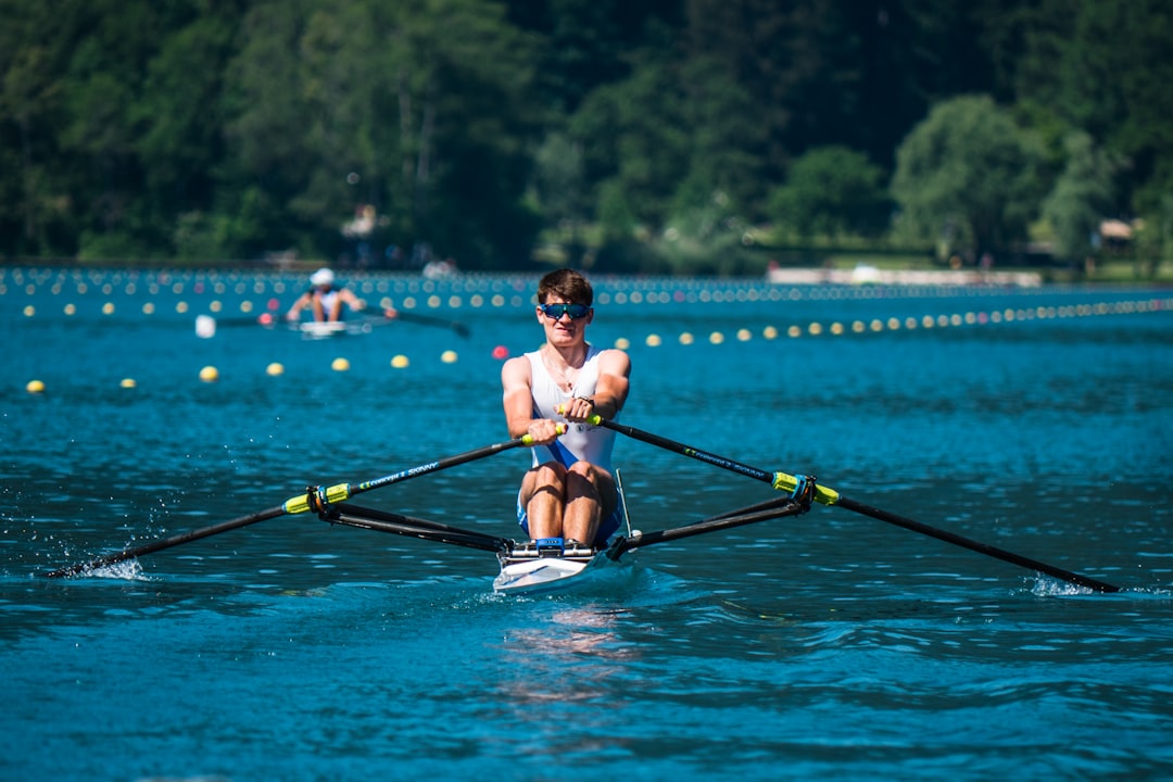 man in blue shorts riding on black kayak on blue body of water during daytime