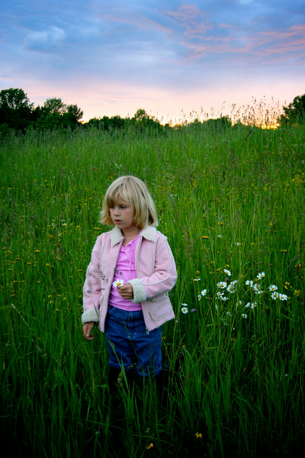 a little girl standing in a field of tall grass