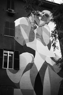 A large-scale mural on a building facade, depicting a flowing natural scene with stylized figures.