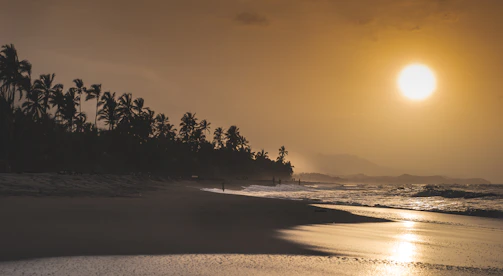A serene beach along the Gulf of Guinea at sunset, with palm-lined shores near Lomé.