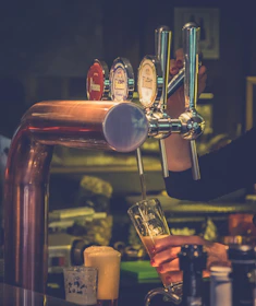 Close-up of a bartender expertly pouring a frothy craft beer from one of the four taps.