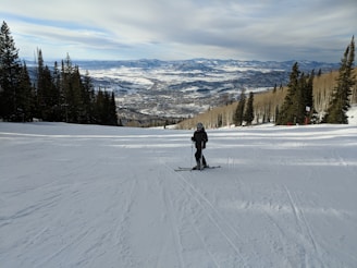 Skier checking The Ski Watch on a snowy slope with pine trees around