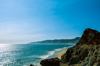 A serene coastal view showcasing a vibrant beach and clear blue sky.
