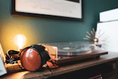 A warm, inviting corner with headphones hanging on a wooden stand next to a small plant.