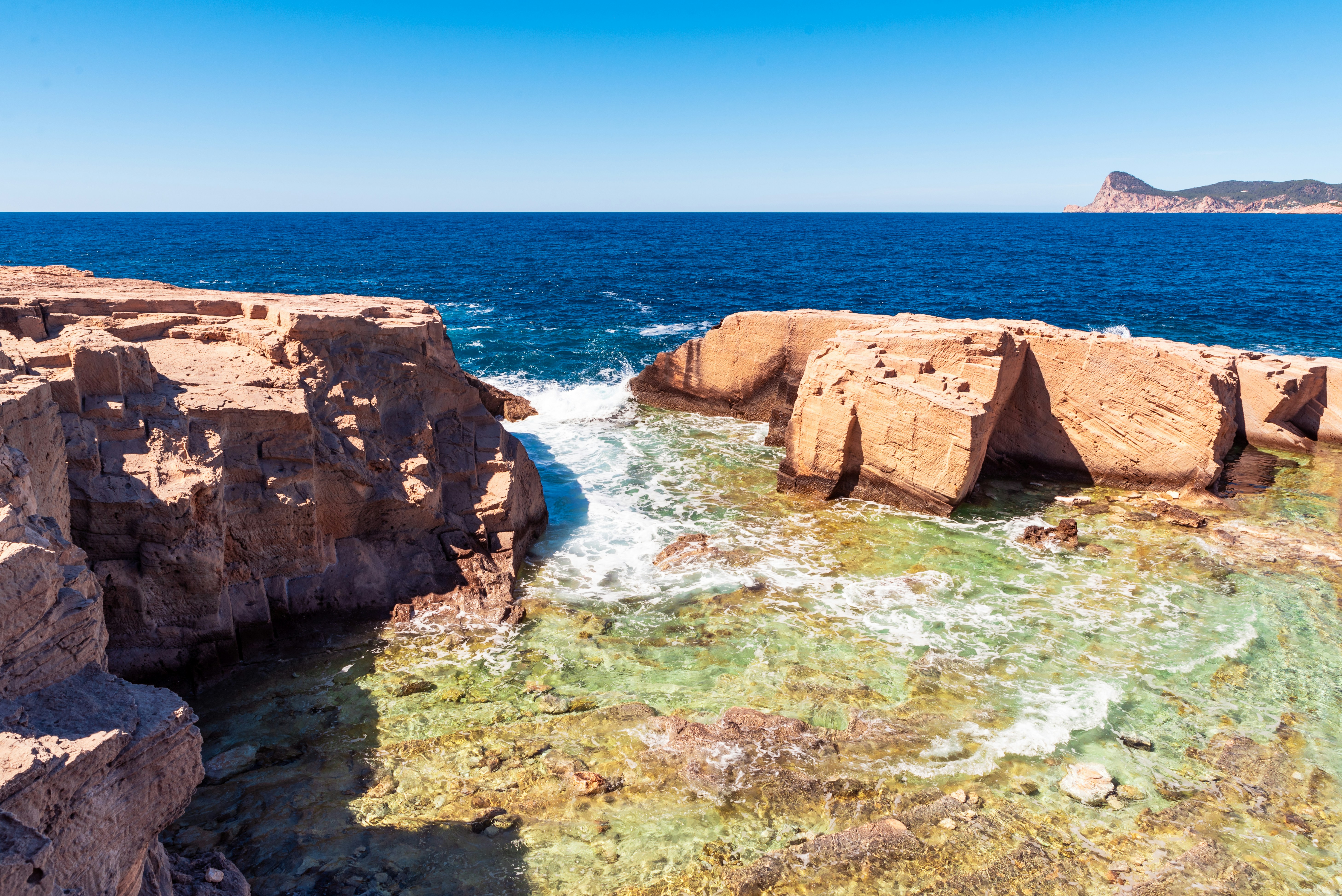 Beach · Ocean waves crashing into a shallow sea cove surround by chiselled rocks.