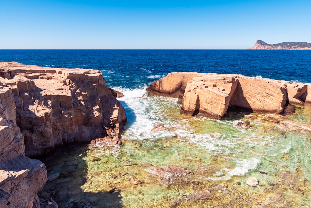 brown rock formation on blue sea under blue sky during daytime