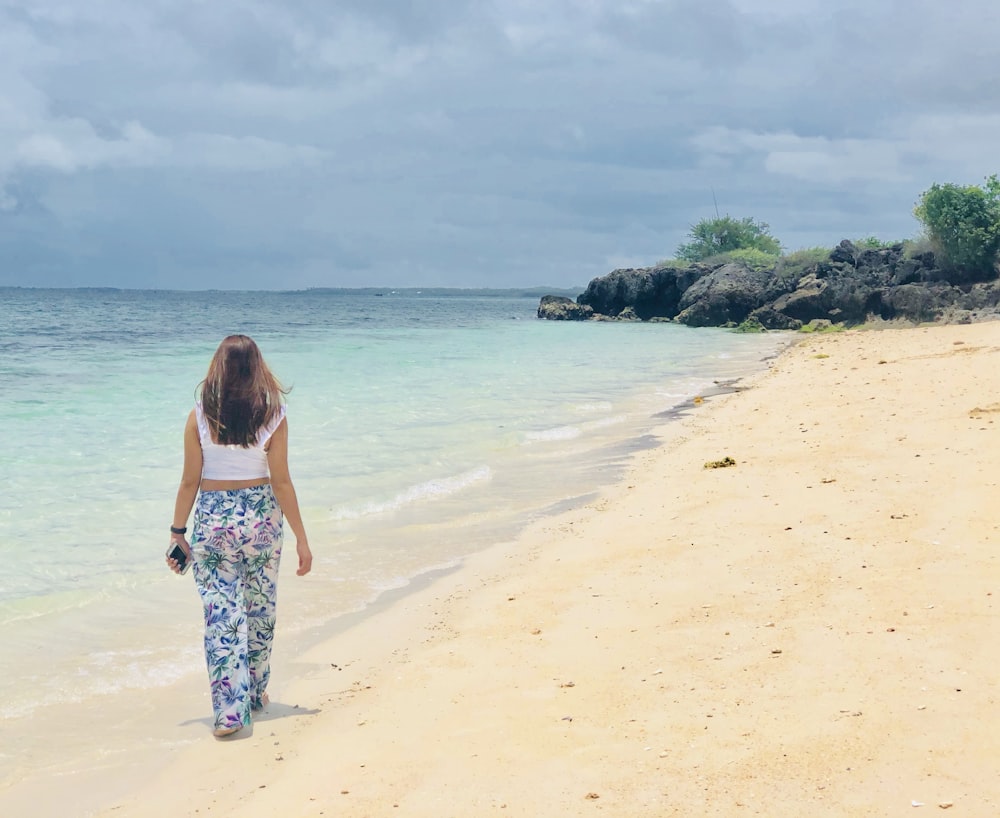 woman in blue and white floral dress standing on beach during daytime