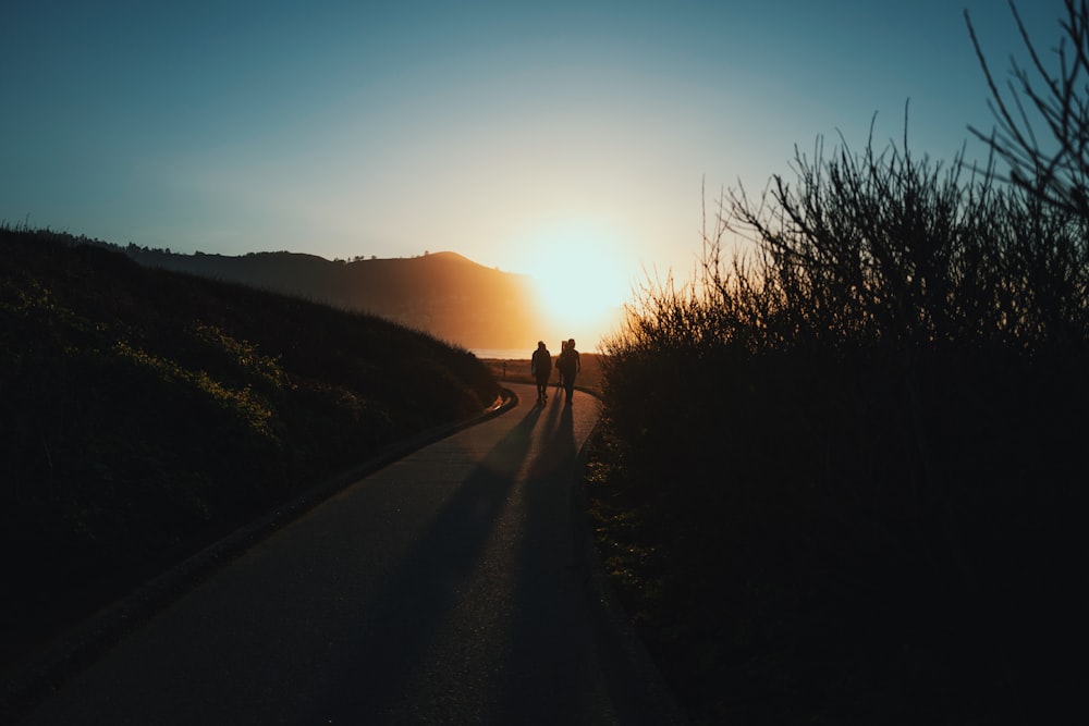 Silueta de la persona que camina por el camino durante la puesta del sol