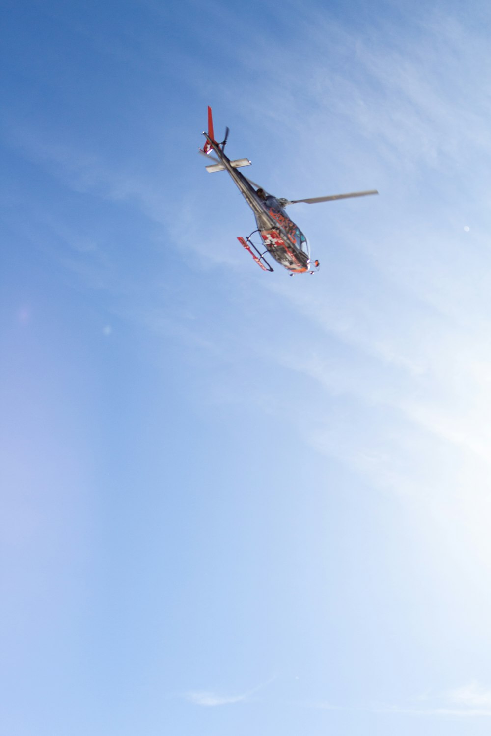 red and white helicopter flying in the sky