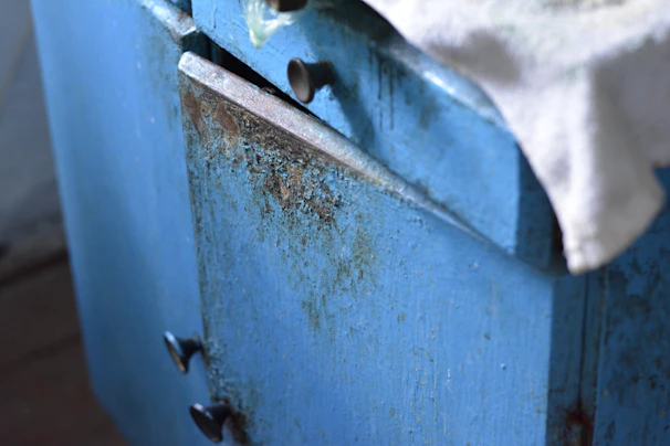 Close-up of chipped cabinet edges and dull surfaces in an old Lancashire kitchen.