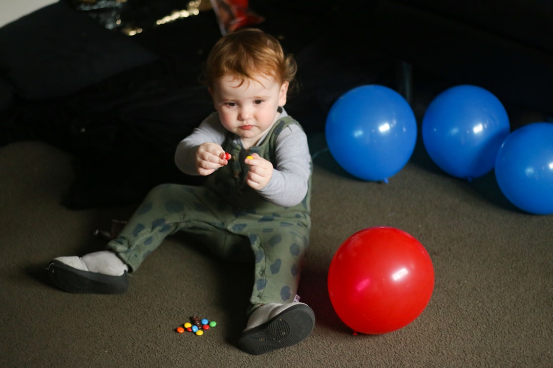 boy in green and white long sleeve shirt sitting on black floor