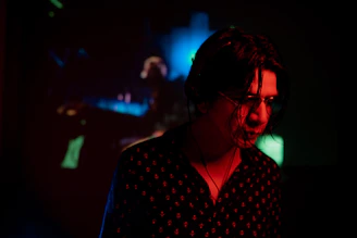 Artist wearing headphones, nodding to music in a dimly lit room with neon accents.