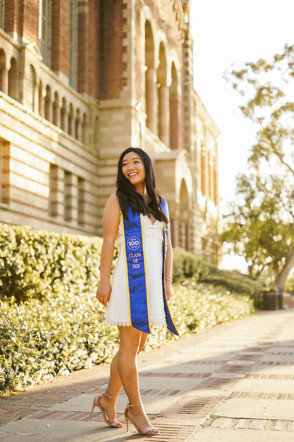 woman in blue and white sleeveless dress standing on sidewalk during daytime