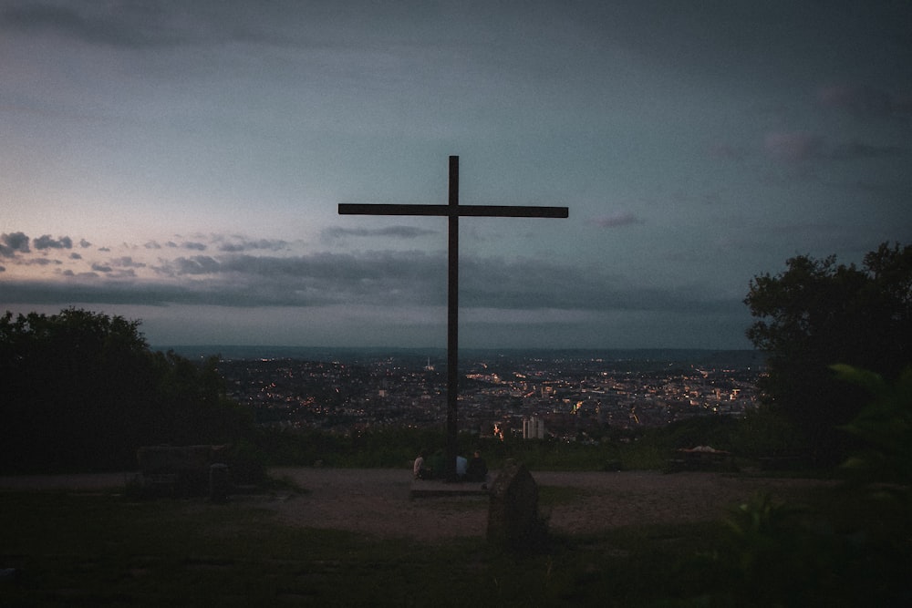 brown wooden cross on green grass field under cloudy sky during daytime