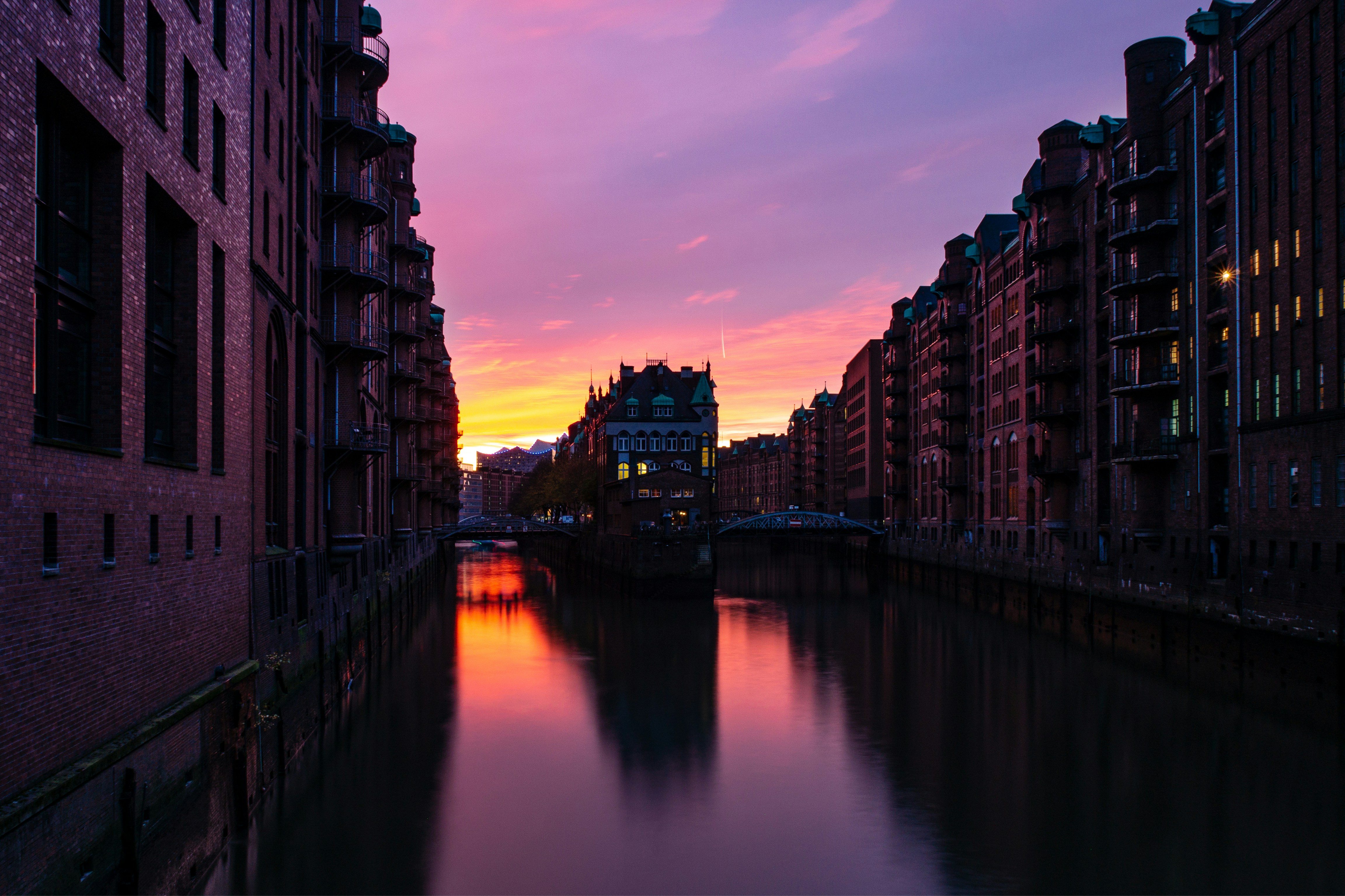 brown concrete building near body of water during sunset, Wasserschloss at Speicherstadt in Hamburg during sunset in autumn.