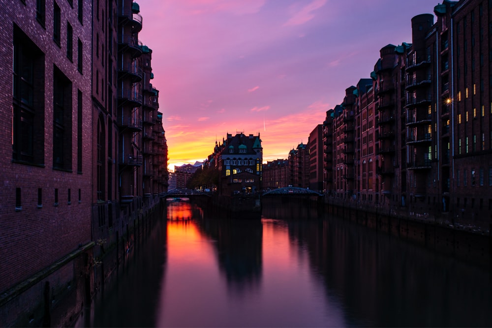 brown concrete building near body of water during sunset