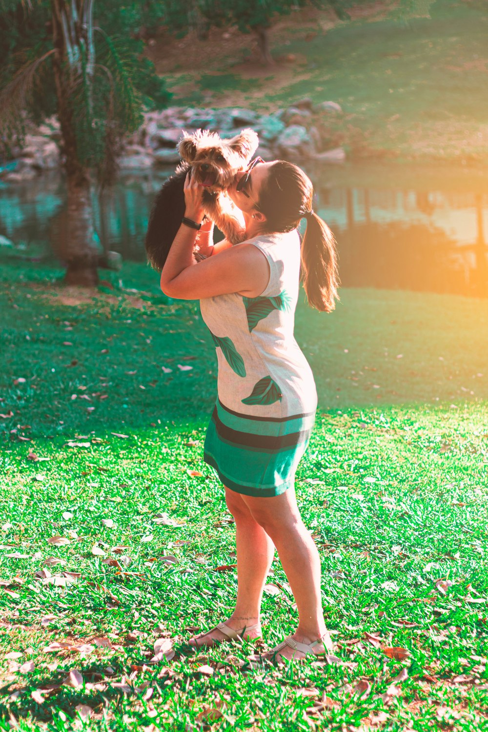 woman in white and teal stripe dress carrying brown dog