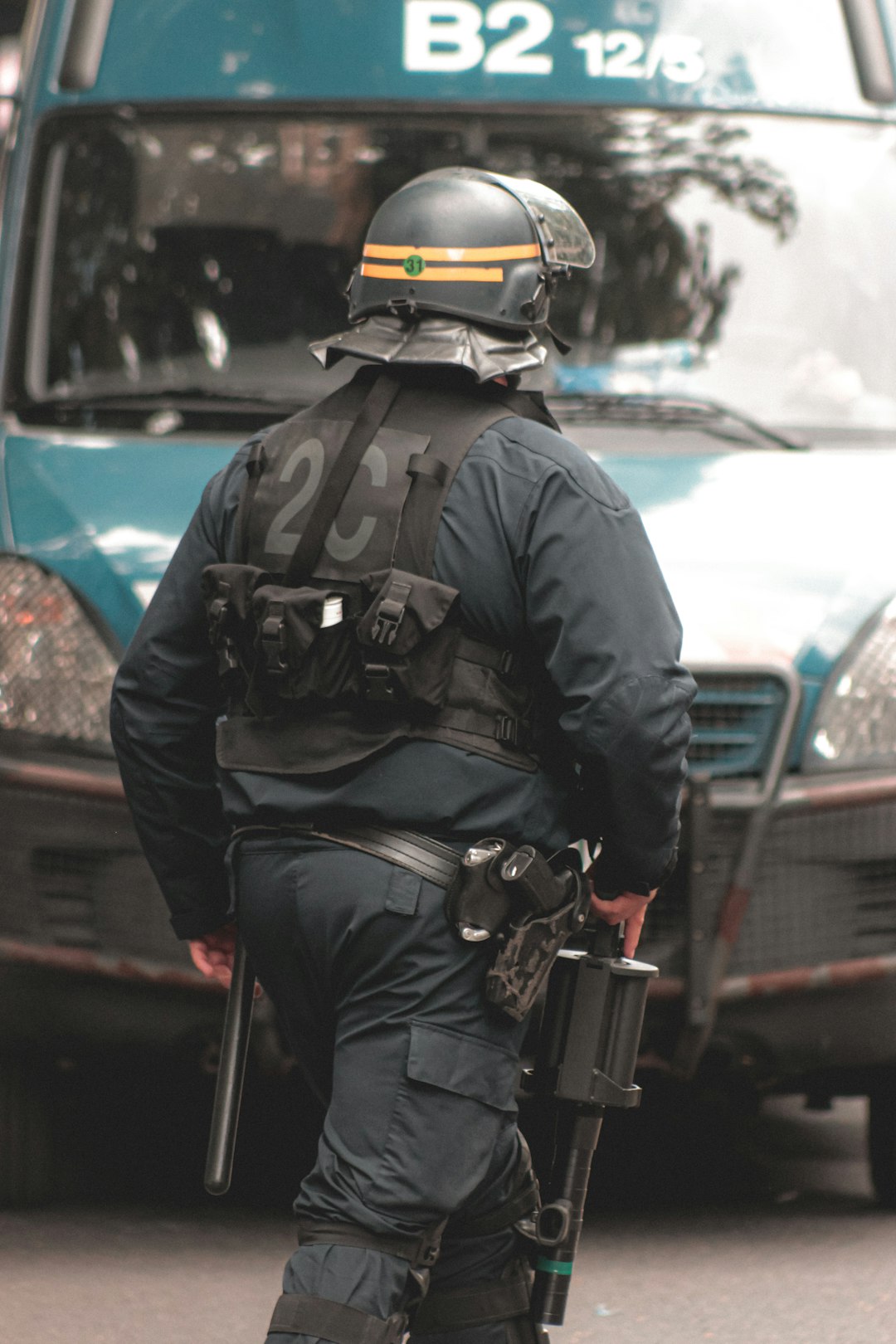 man in black jacket and yellow helmet standing beside blue car during daytime