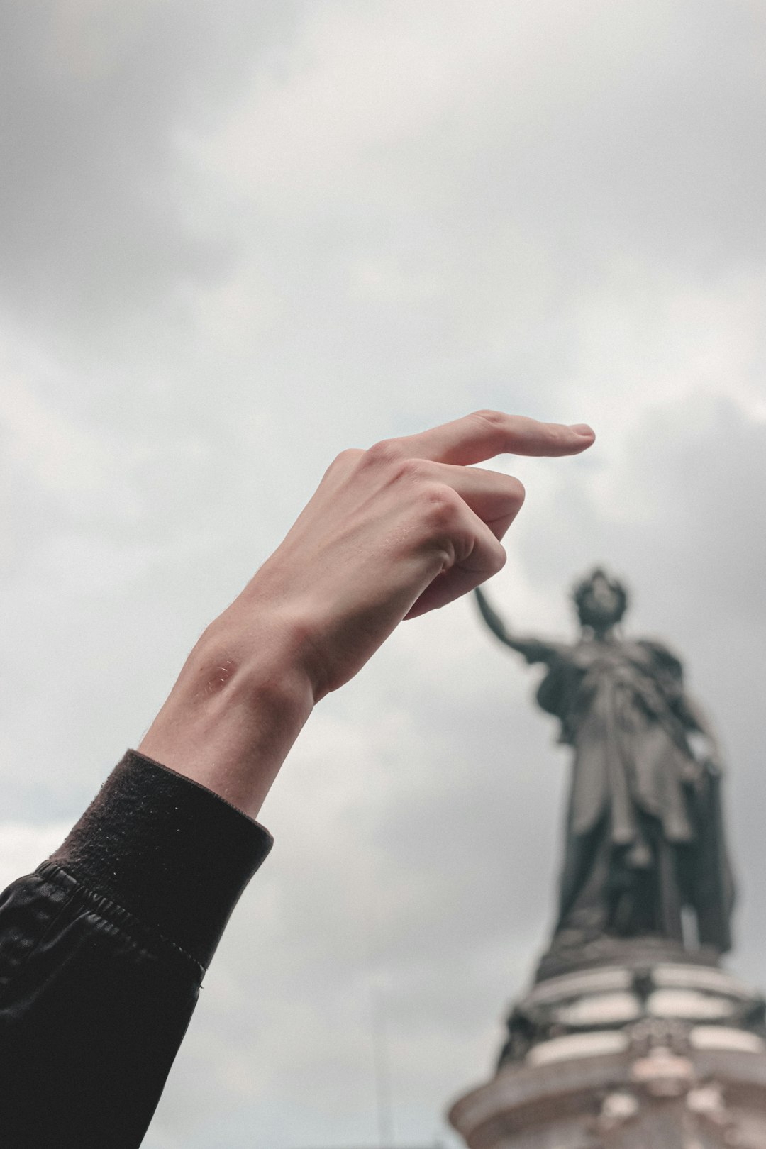 person in black long sleeve shirt holding white flower under white clouds during daytime