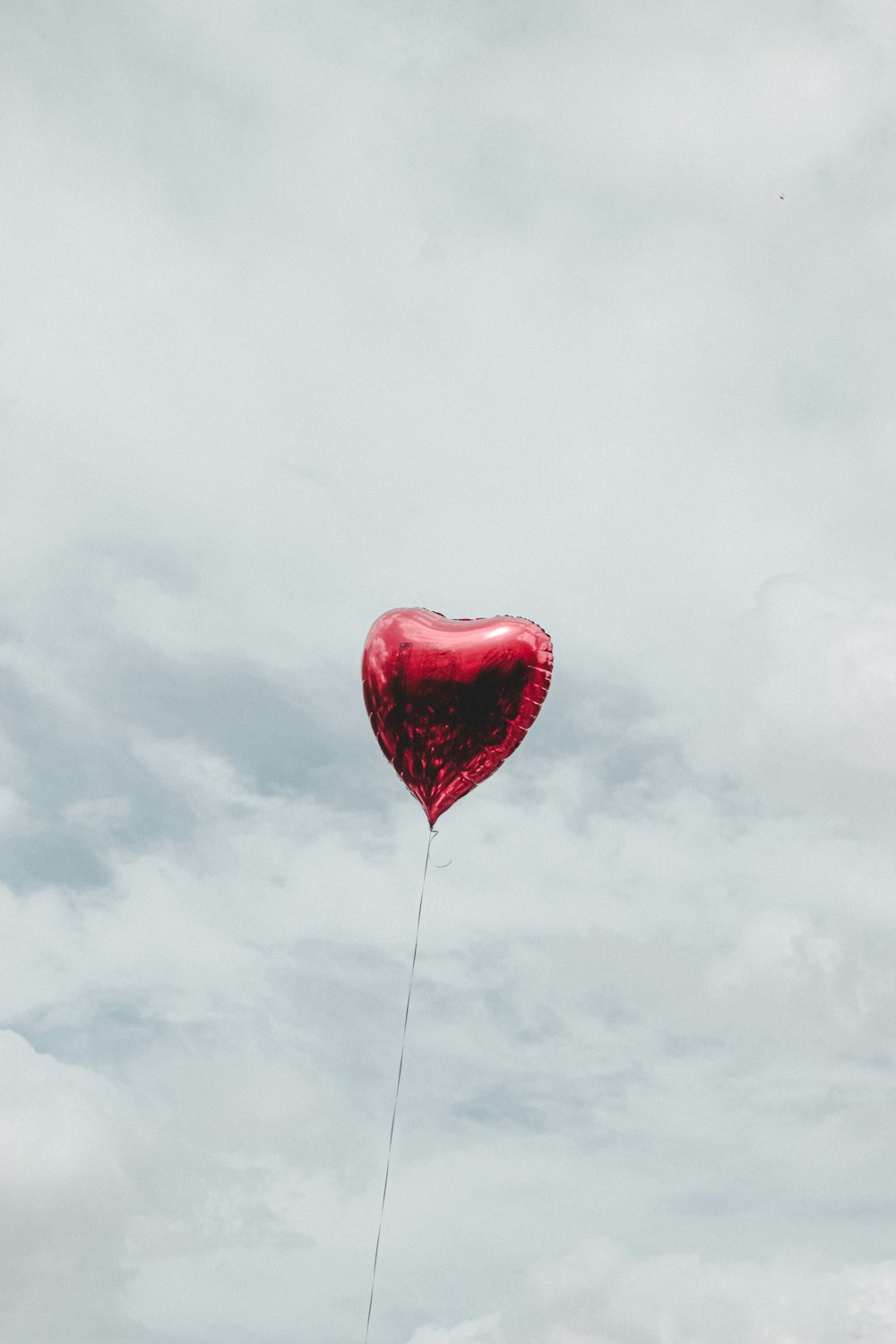 balão vermelho do coração sob o céu nublado