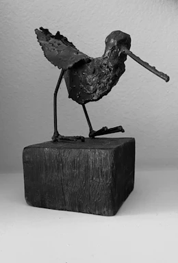 A detailed metal animal sculpture perched gracefully on a wooden shelf.