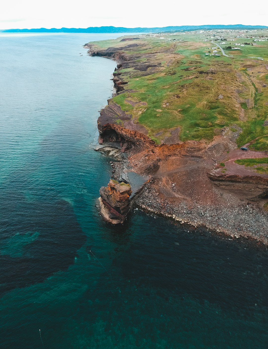 brown and green rock formation beside blue sea during daytime