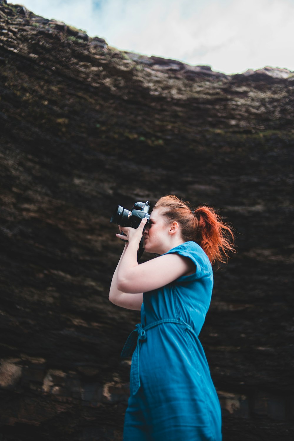 woman in blue sleeveless dress taking photo using black dslr camera