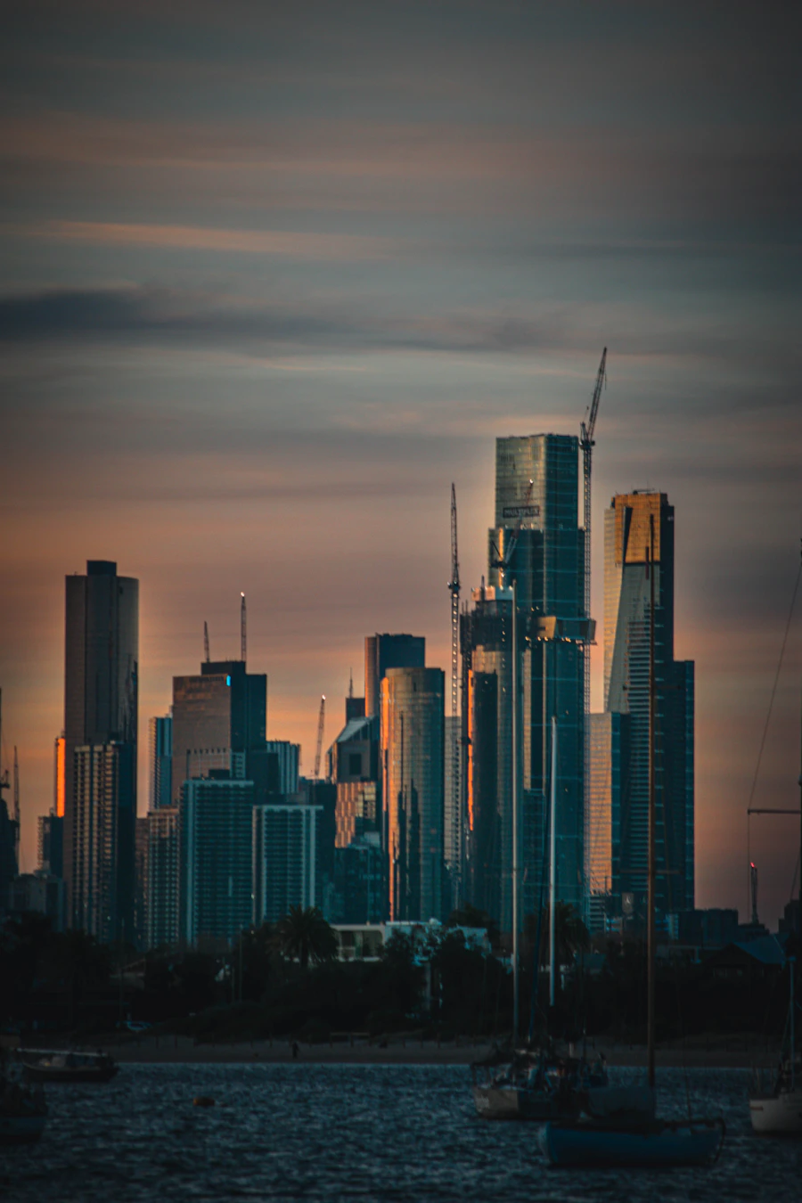 Modern skyline rising beside a marina at sunset