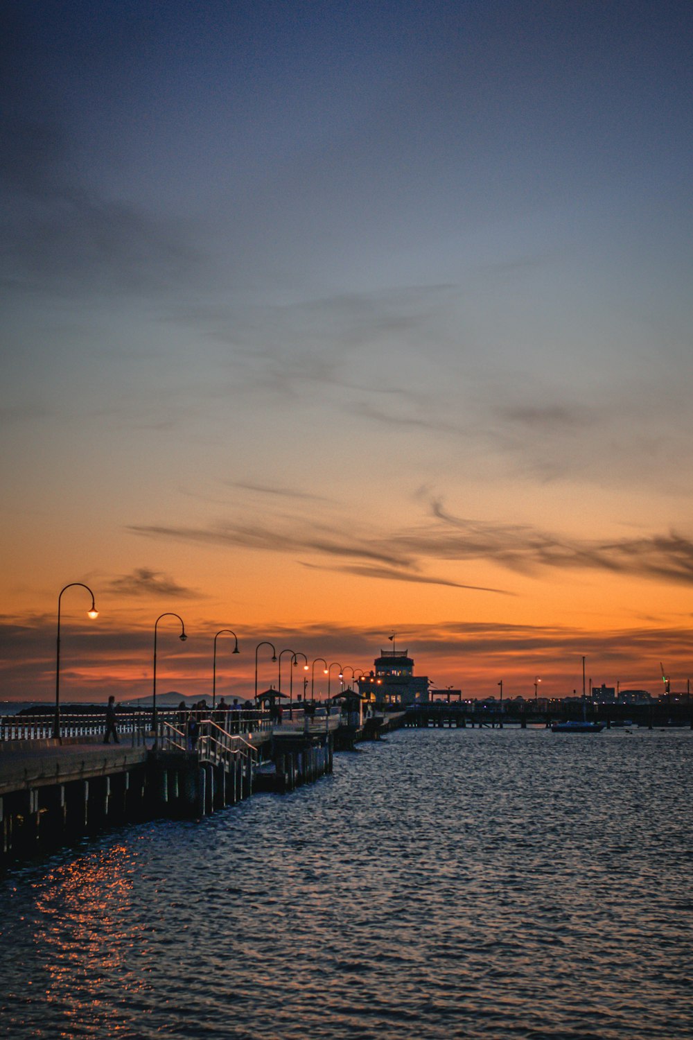 Silhouette von Menschen, die während des Sonnenuntergangs auf dem Dock spazieren gehen