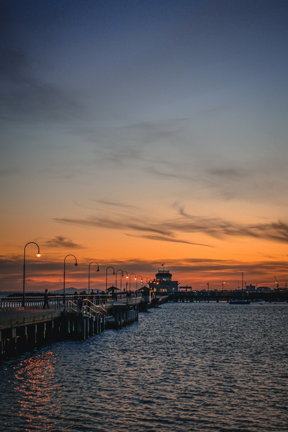 silhouette of people walking on dock during sunset