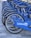 A row of blue bicycles is aligned on a tiled surface, each bicycle featuring the LinkedIn logo prominently displayed on the side panels. The bicycles are neatly arranged, suggesting they are part of a bike-sharing program or rental service.