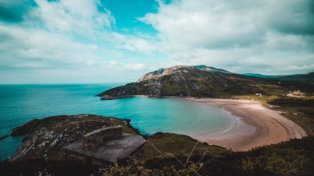 green and brown mountain beside body of water under blue sky during daytime