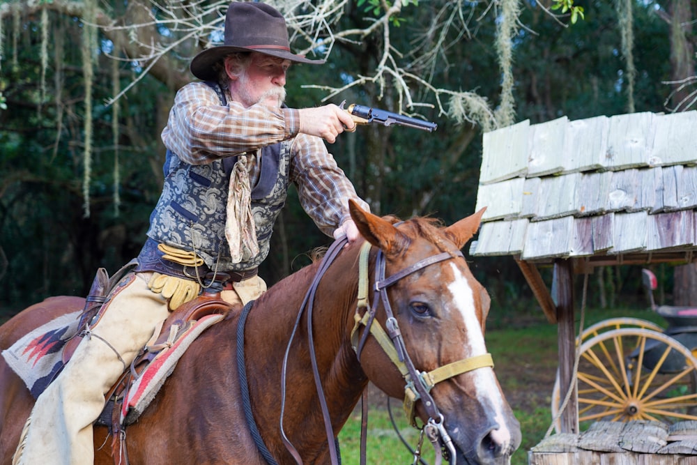 man in black and white plaid dress shirt riding brown horse during daytime